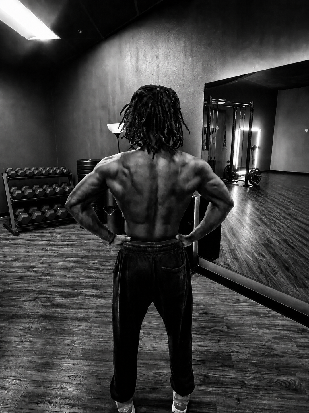 Kenny, shirtless and back-facing in a gym, shown in black and white